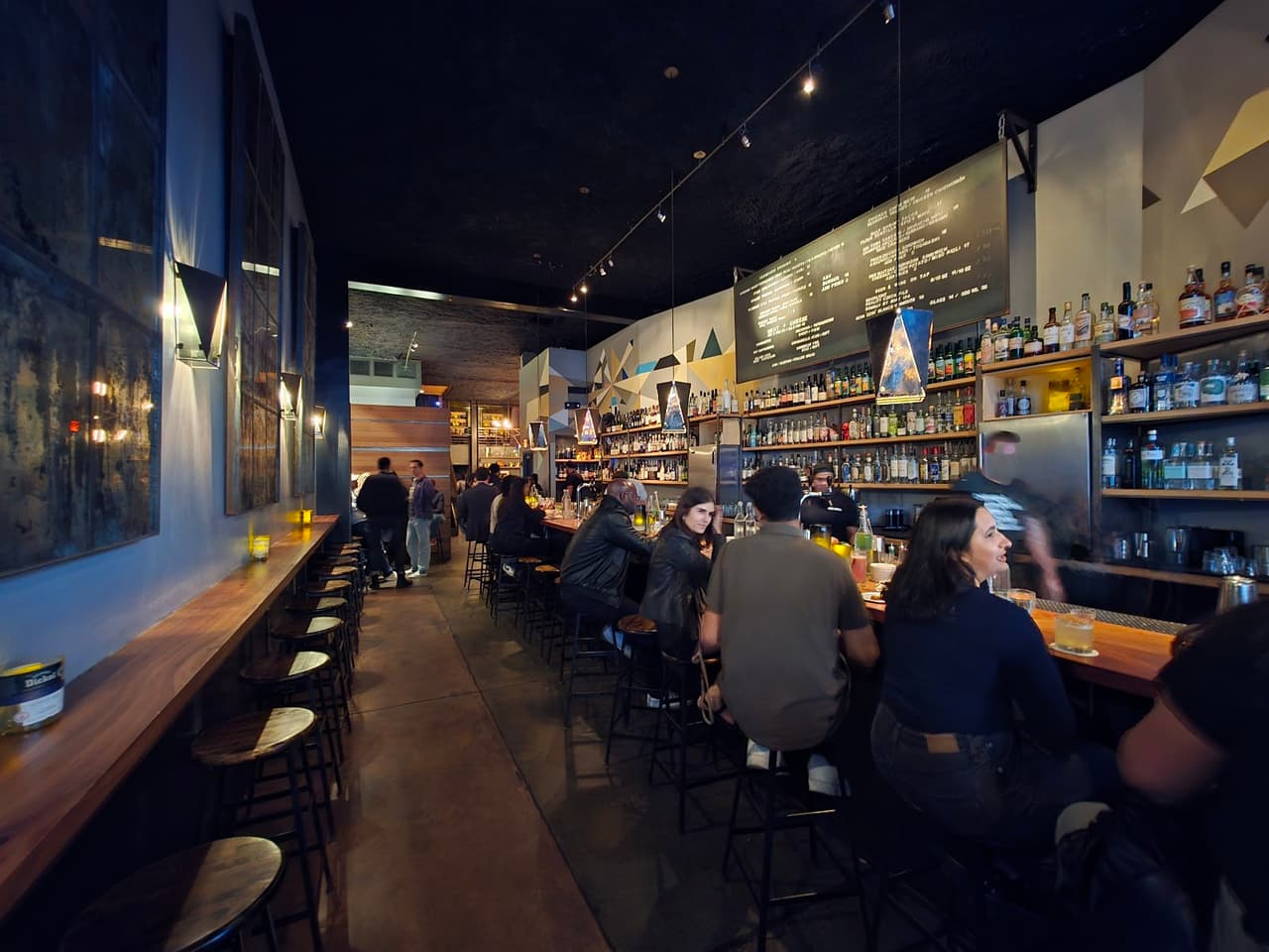 Busy bar with patrons seated along a stocked counter