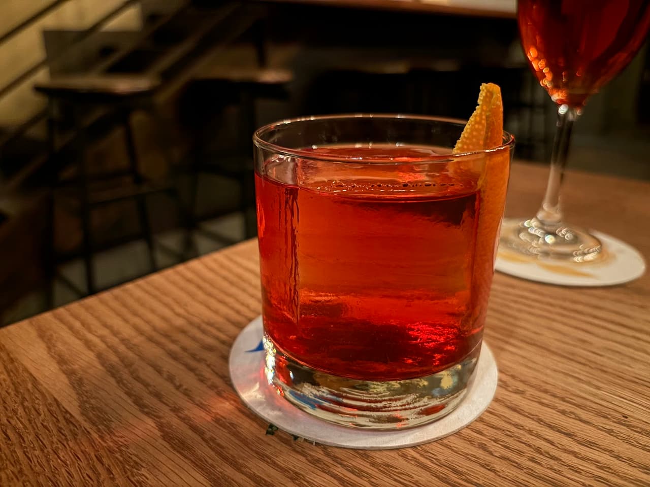 Close-up of a red cocktail with orange garnish on a wooden table in San Francisco