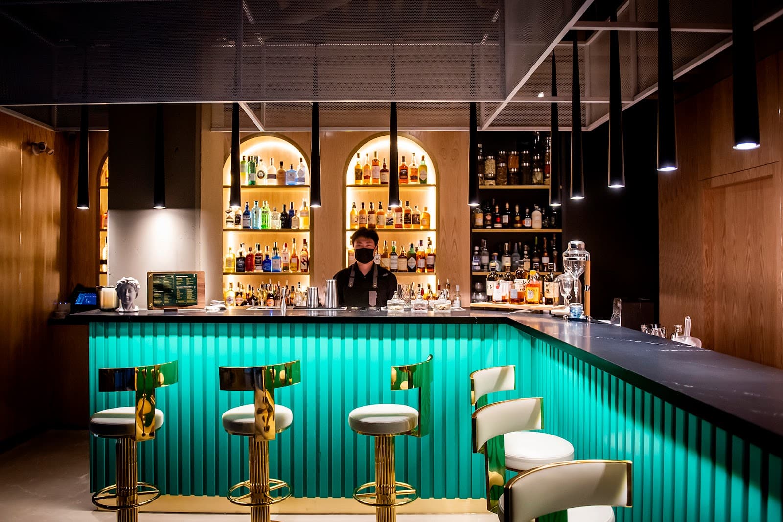 Modern bar with teal counter and illuminated shelves of liquor bottles