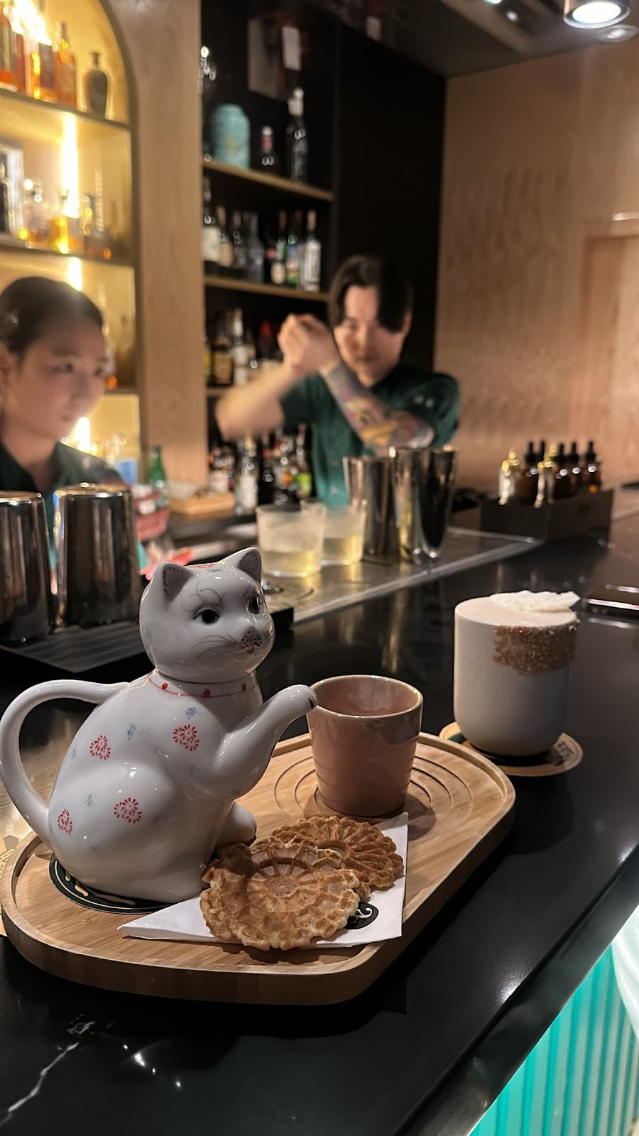 Bar counter with ceramic cat teapot, cookies, and bartender in action in Toronto