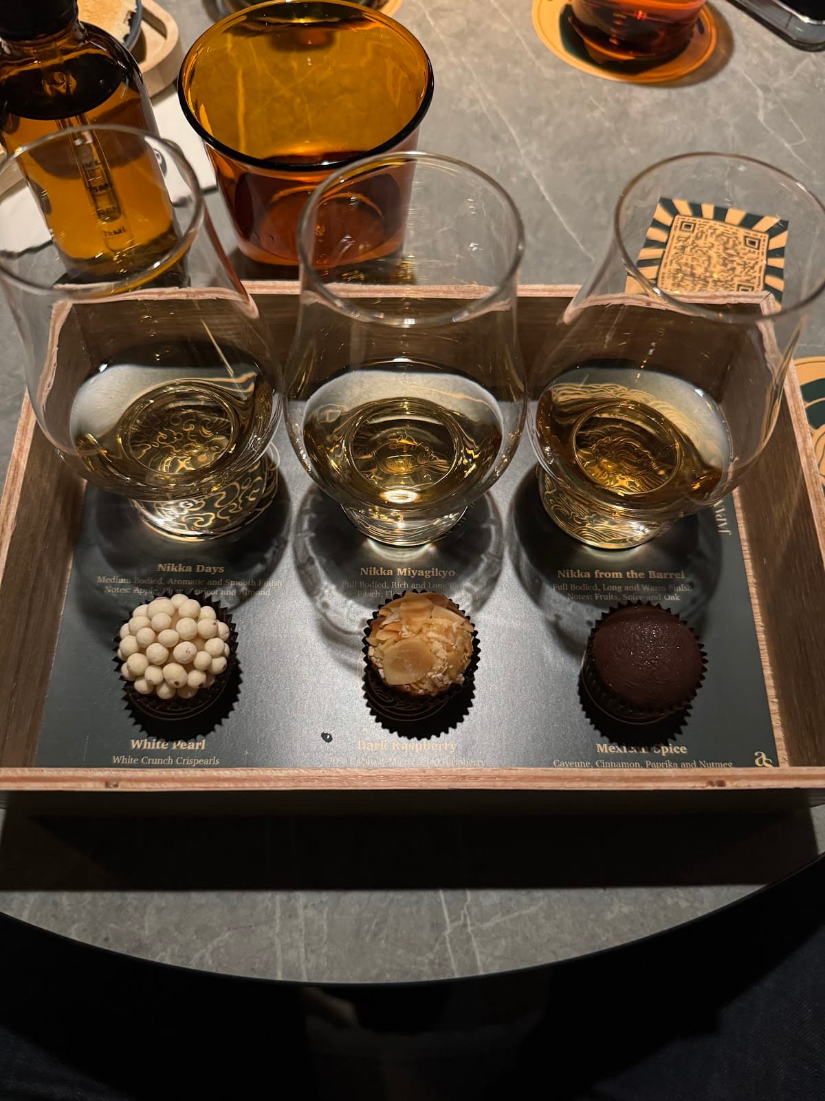 Tray with three whiskey glasses and chocolates on a marble table in Toronto