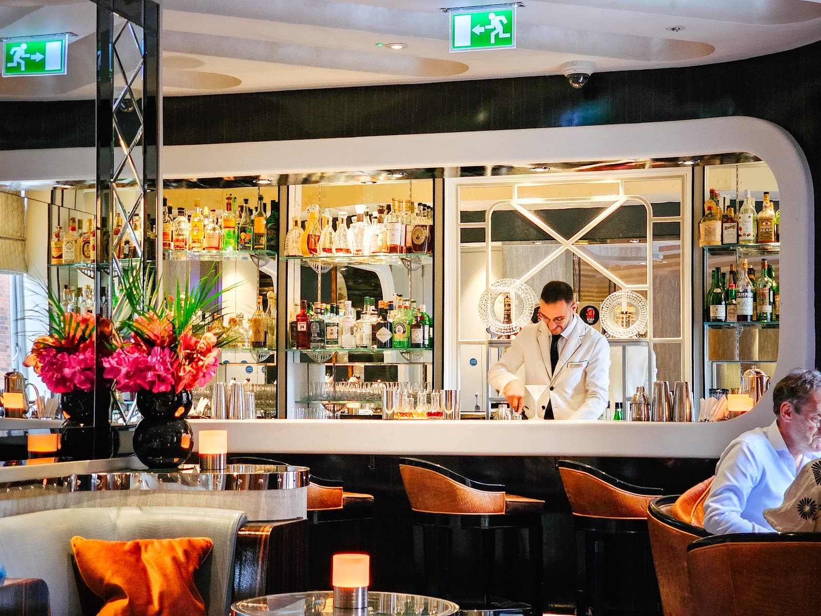 Elegant bar interior with bartender preparing a cocktail, bottles lined up in London