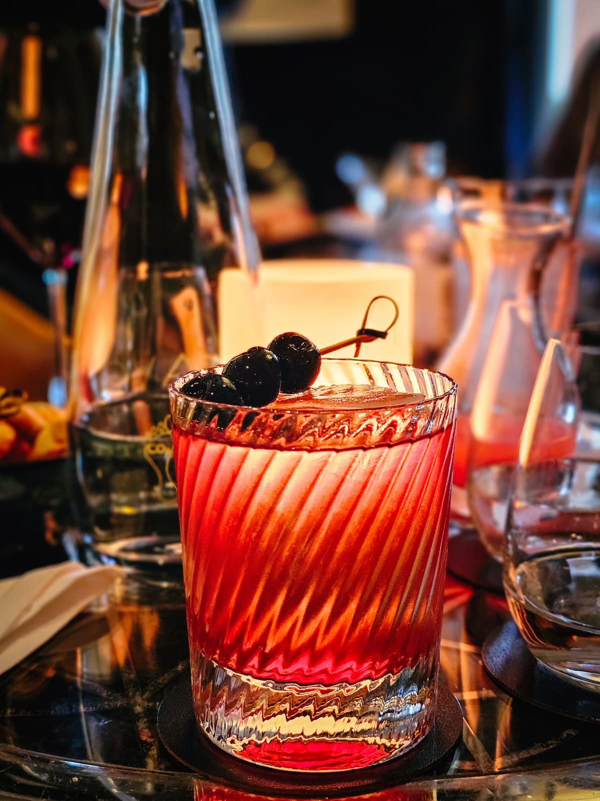 Elegant cocktail with cherries on a reflective bar surface in London