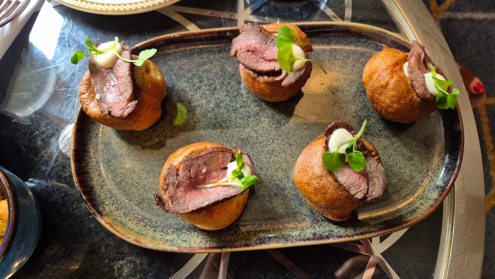 Plate of appetizers with meat slices on dough puffs on a table in London