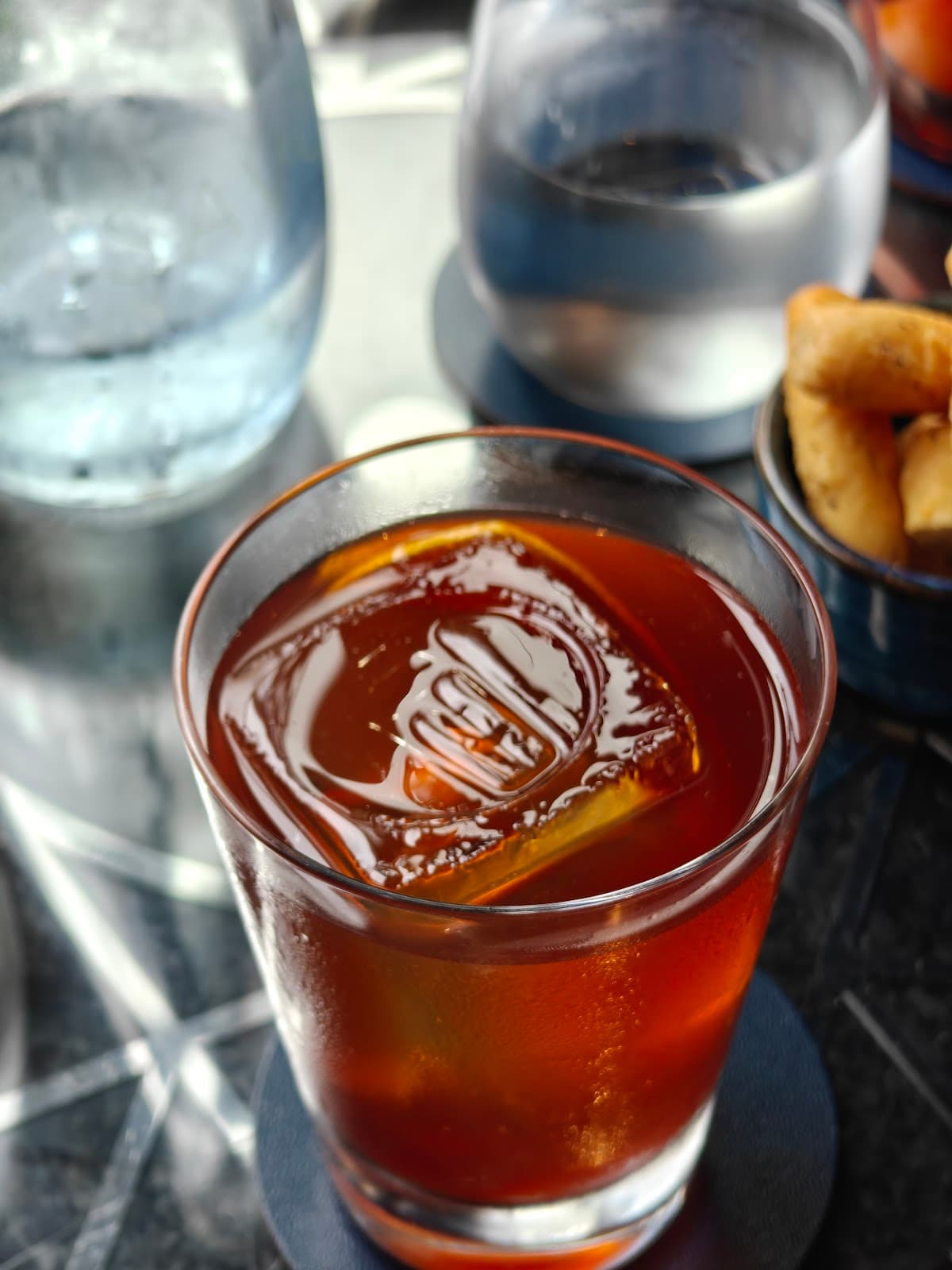 Close-up of a cocktail with a clear ice cube on a dark table in London