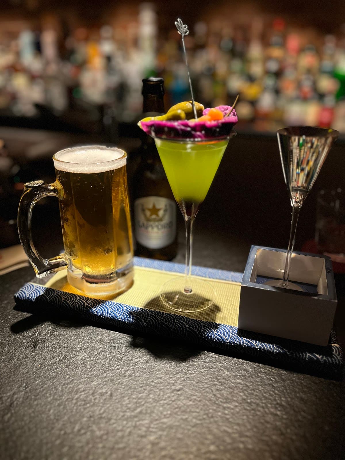 Cocktail with vibrant garnish and beer on bar counter in London