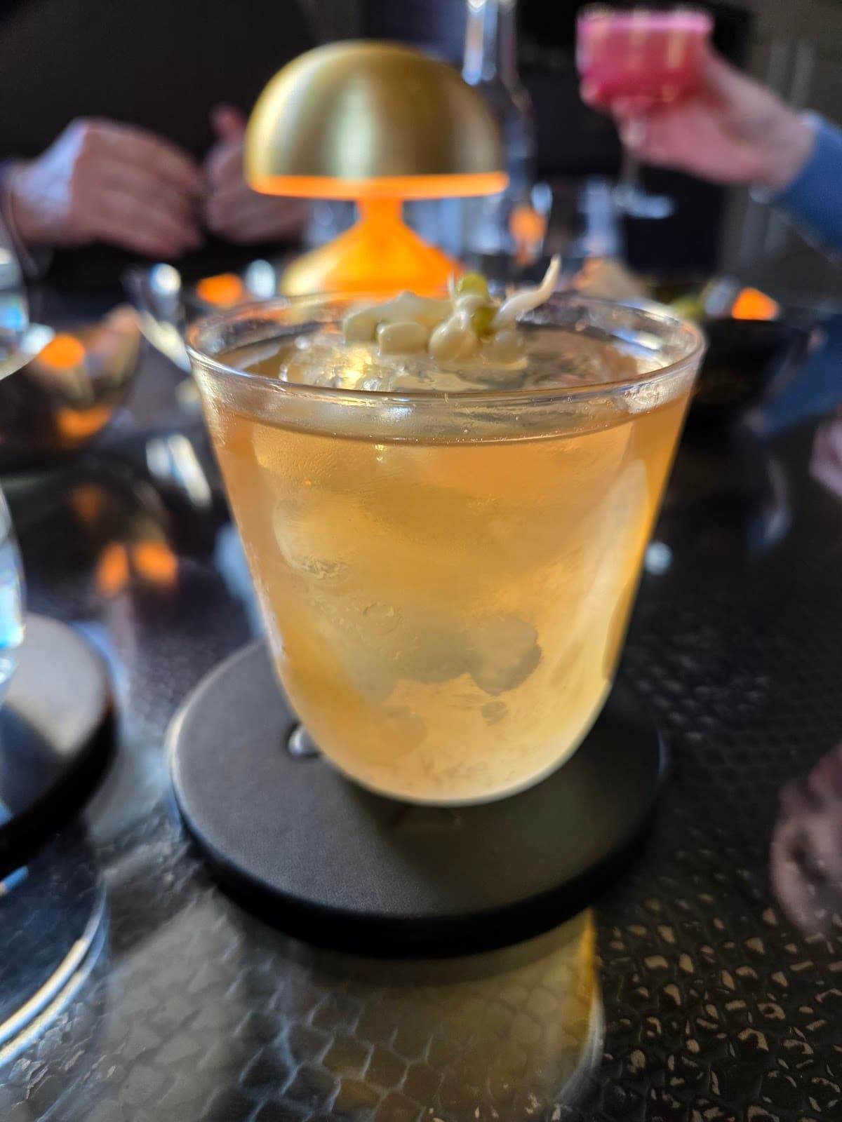 Close-up of a cocktail with a garnish on a reflective table with ambient lighting in London