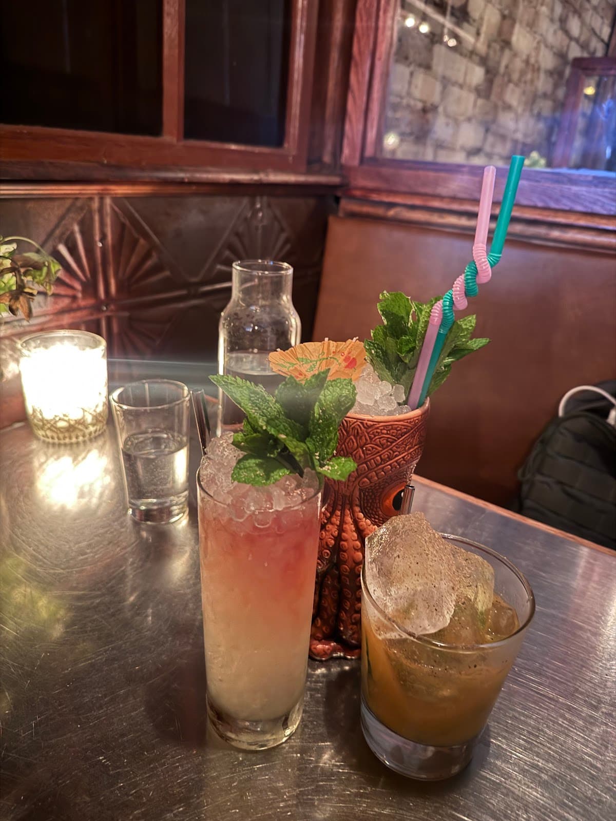 Cocktail selection on a metal table in a dimly lit bar in New York