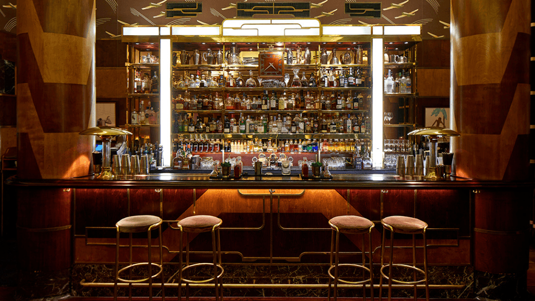 Elegant cocktail bar with backlit shelves and bar stools