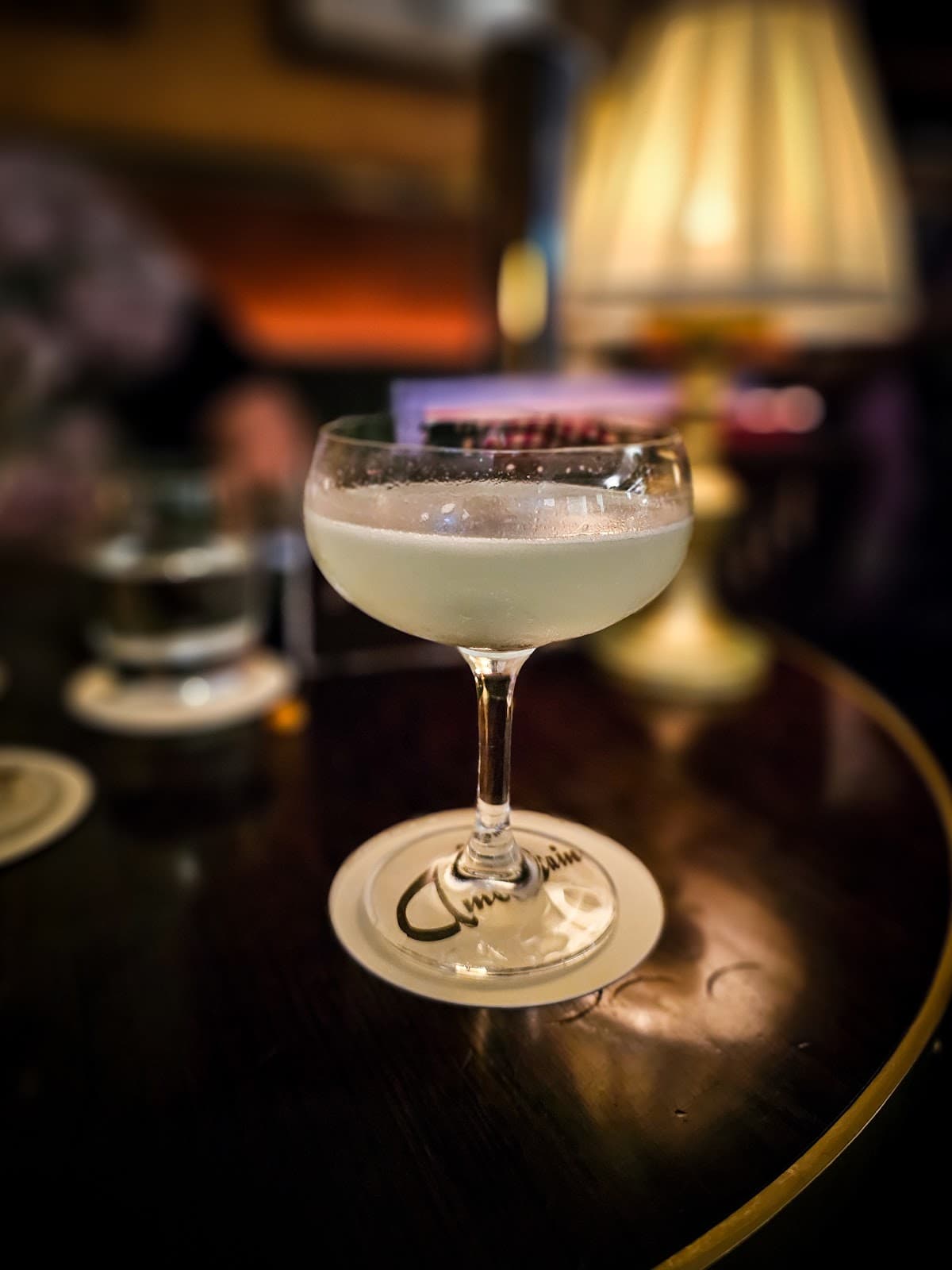 Close-up of a cocktail on a table with dim lighting and a lamp in London