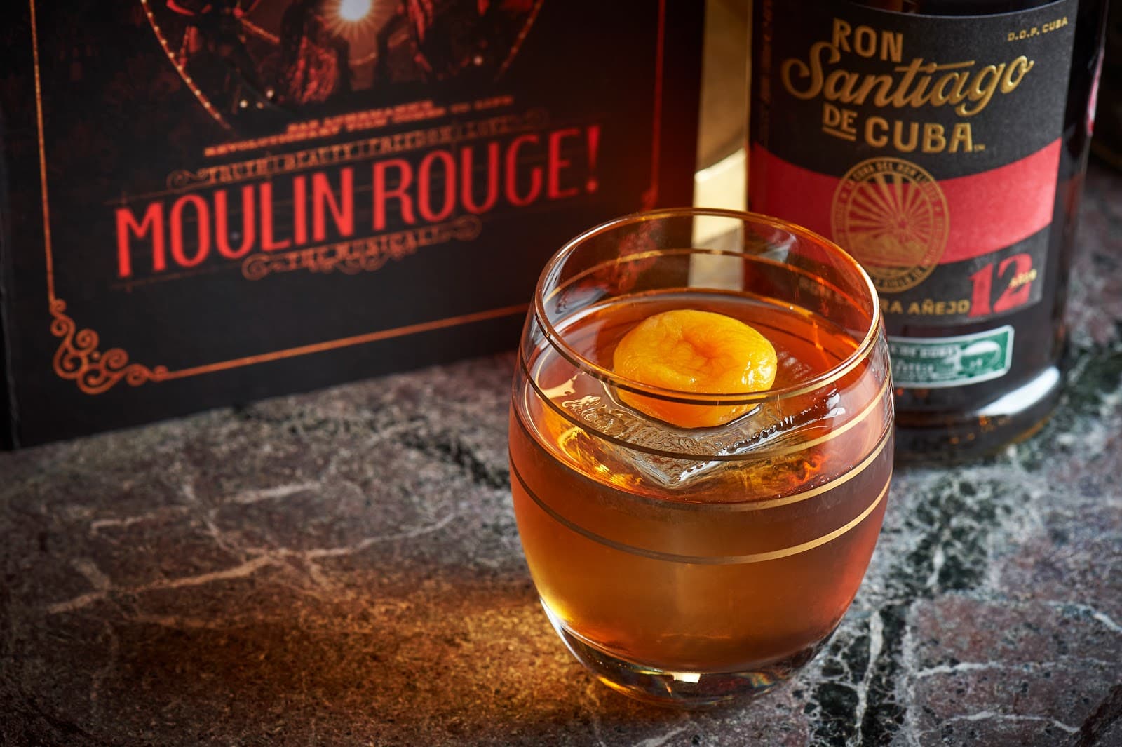 Cocktail with amber liquid and apricot garnish on marble table in London