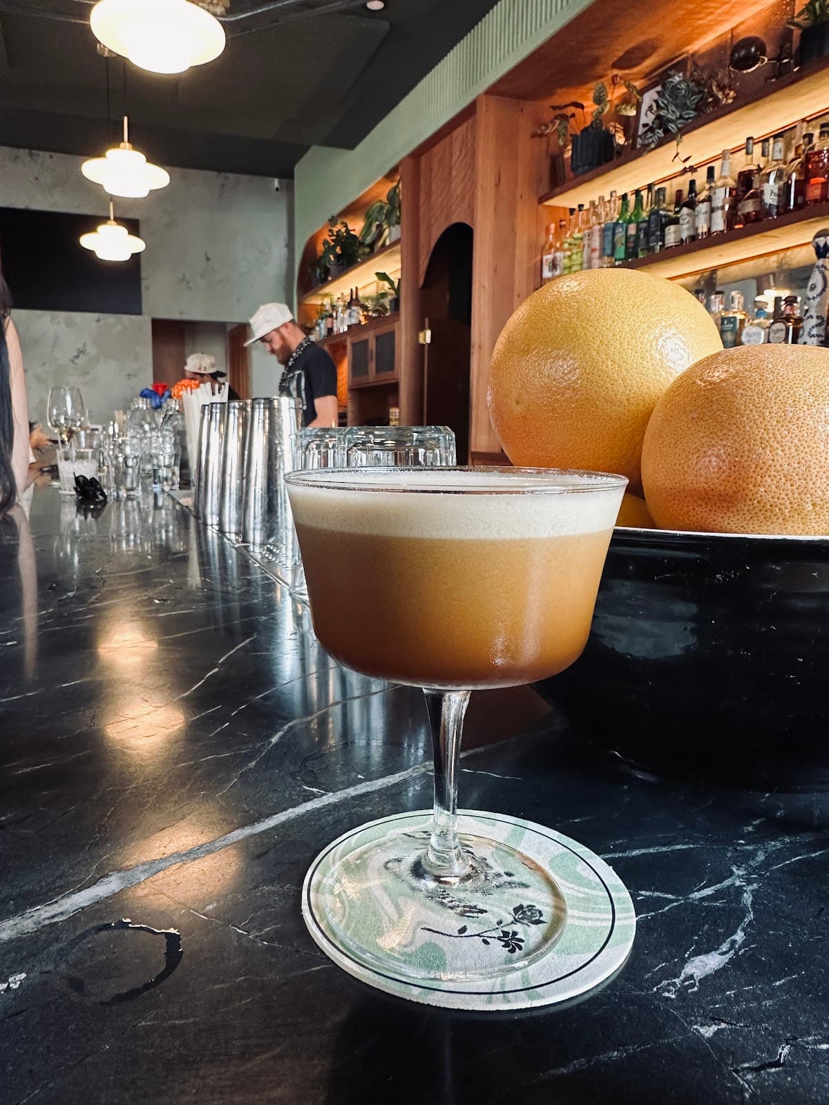 Close-up of cocktail on bar counter with bottles and lighting in background in San Francisco