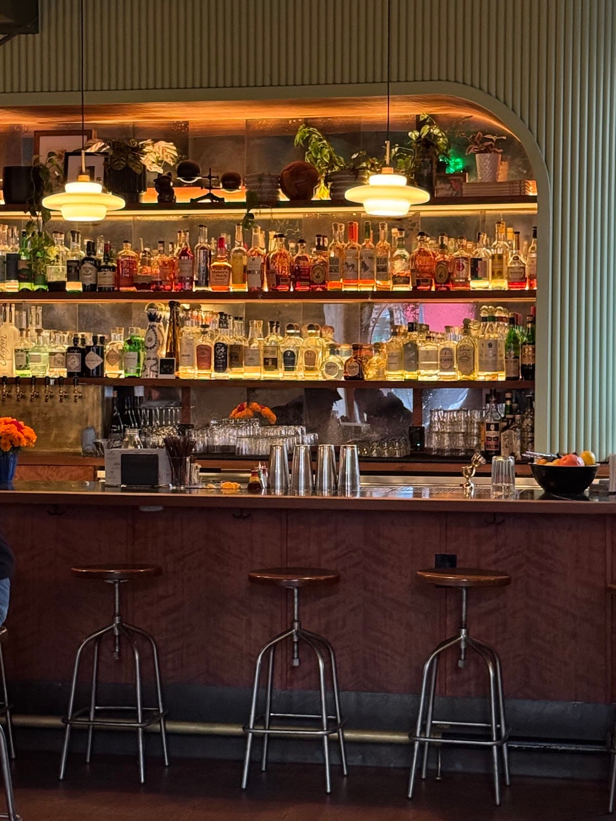 Stylish bar with bottles and seating under warm lighting