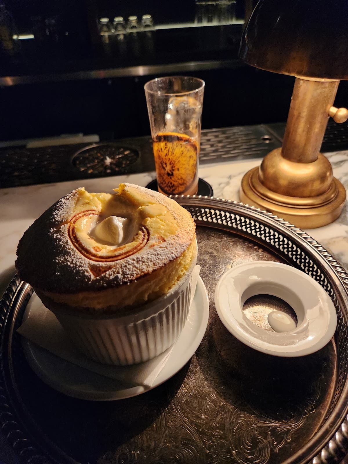 Plate with dessert and glass on a dimly lit bar counter in Toronto