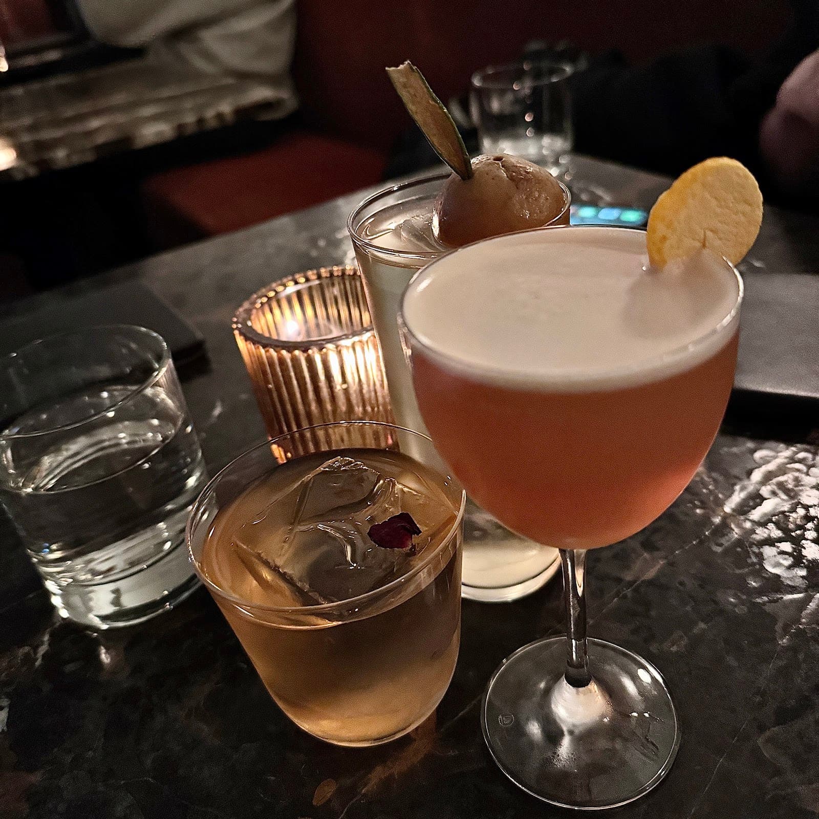 Assorted cocktails on a dimly lit marble table in a premium bar setting in Toronto