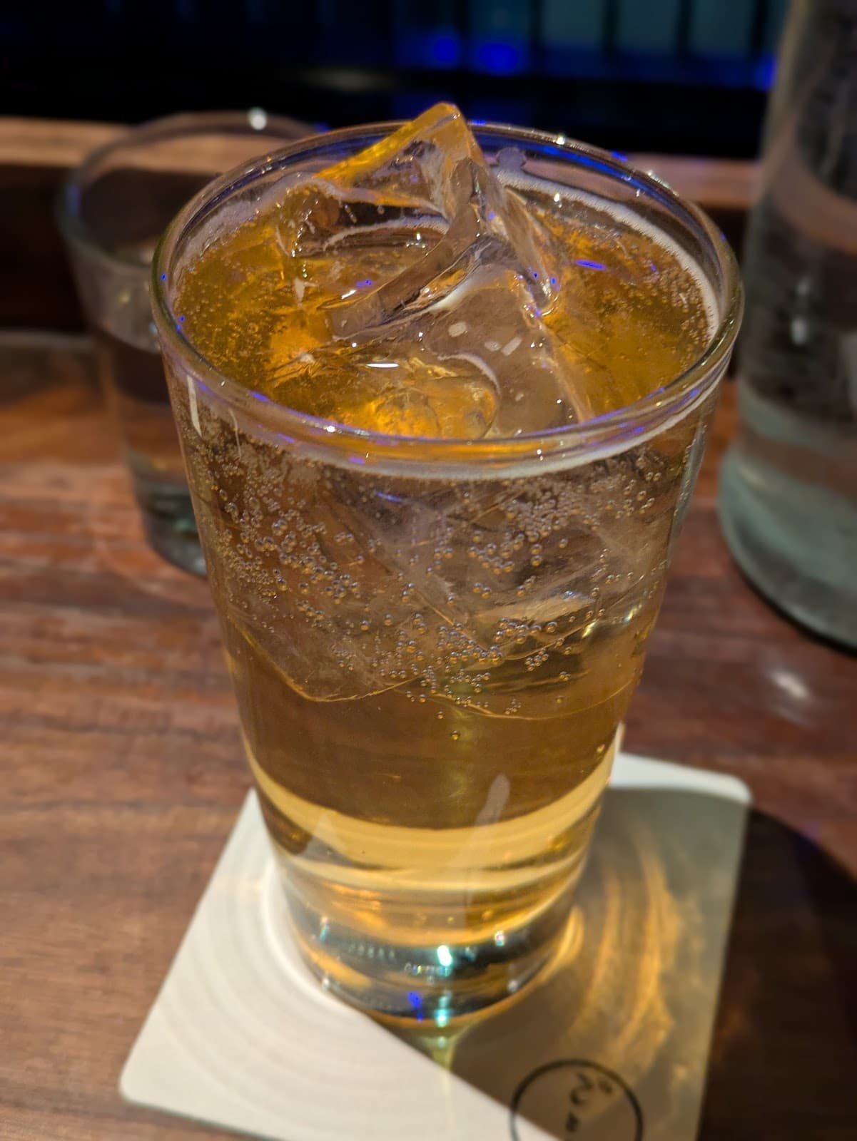 Close-up of a cocktail with ice cubes on a wooden bar counter in New York