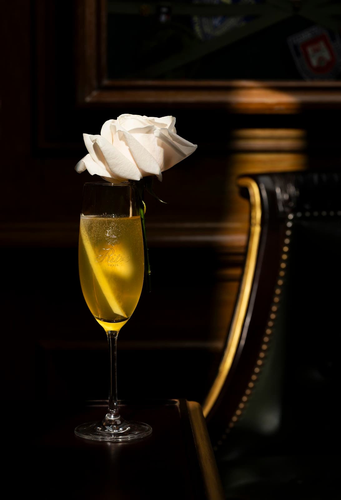 Chic cocktail glass with yellow drink topped by white rose in upscale bar setting in Paris