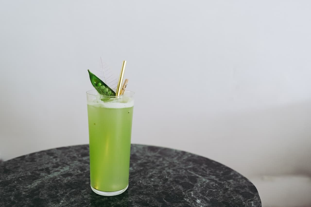 Green cocktail with leaf garnish on a marble table in San Francisco