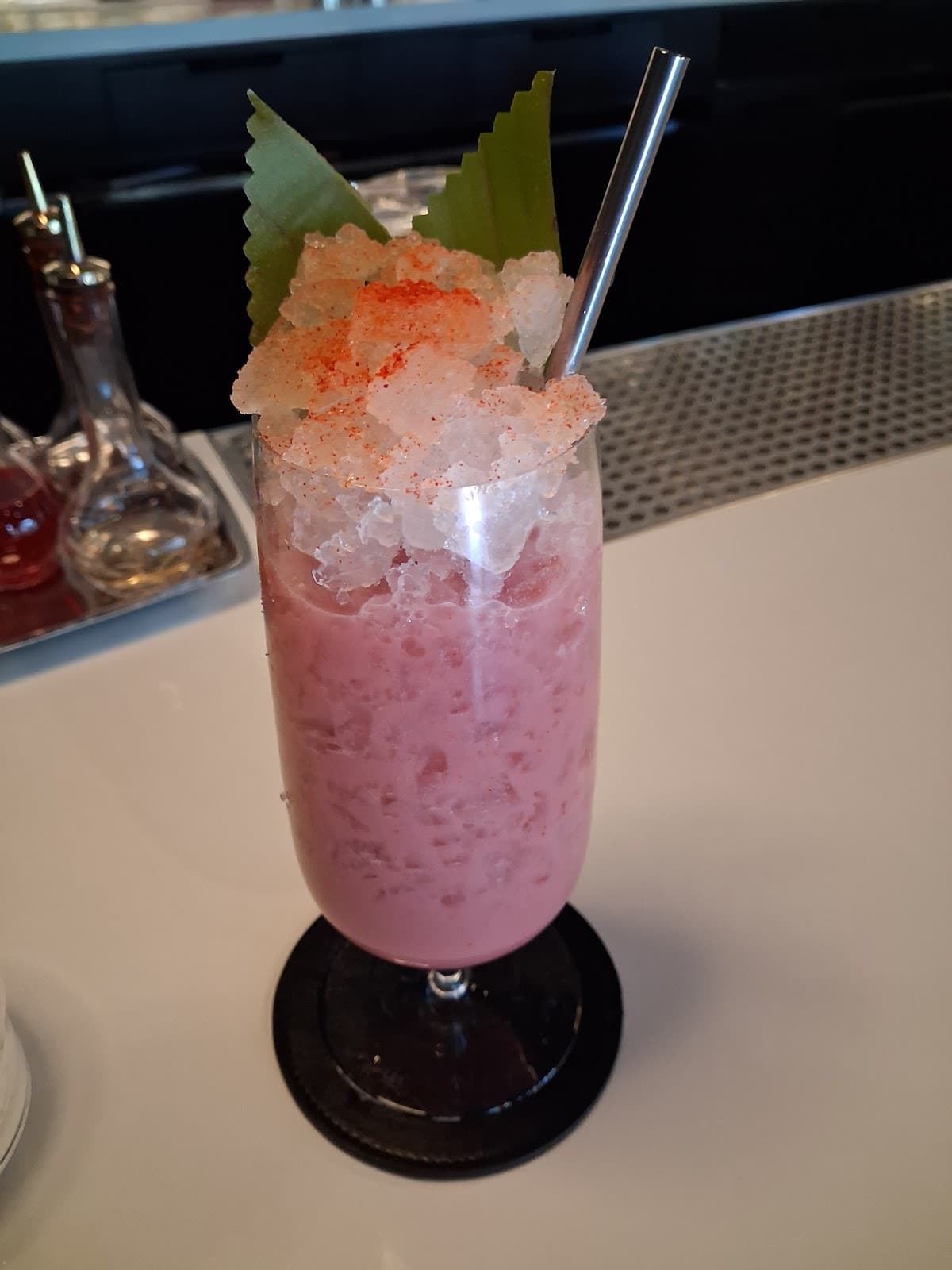 Pink cocktail with crushed ice and green garnish on a bar counter in San Francisco