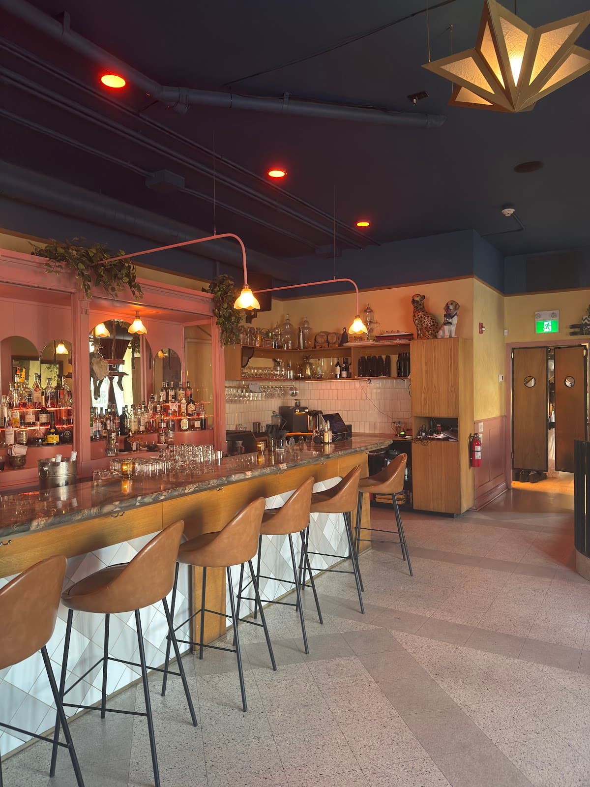 Elegant bar counter with leather stools and hanging lights in a cocktail bar in Toronto