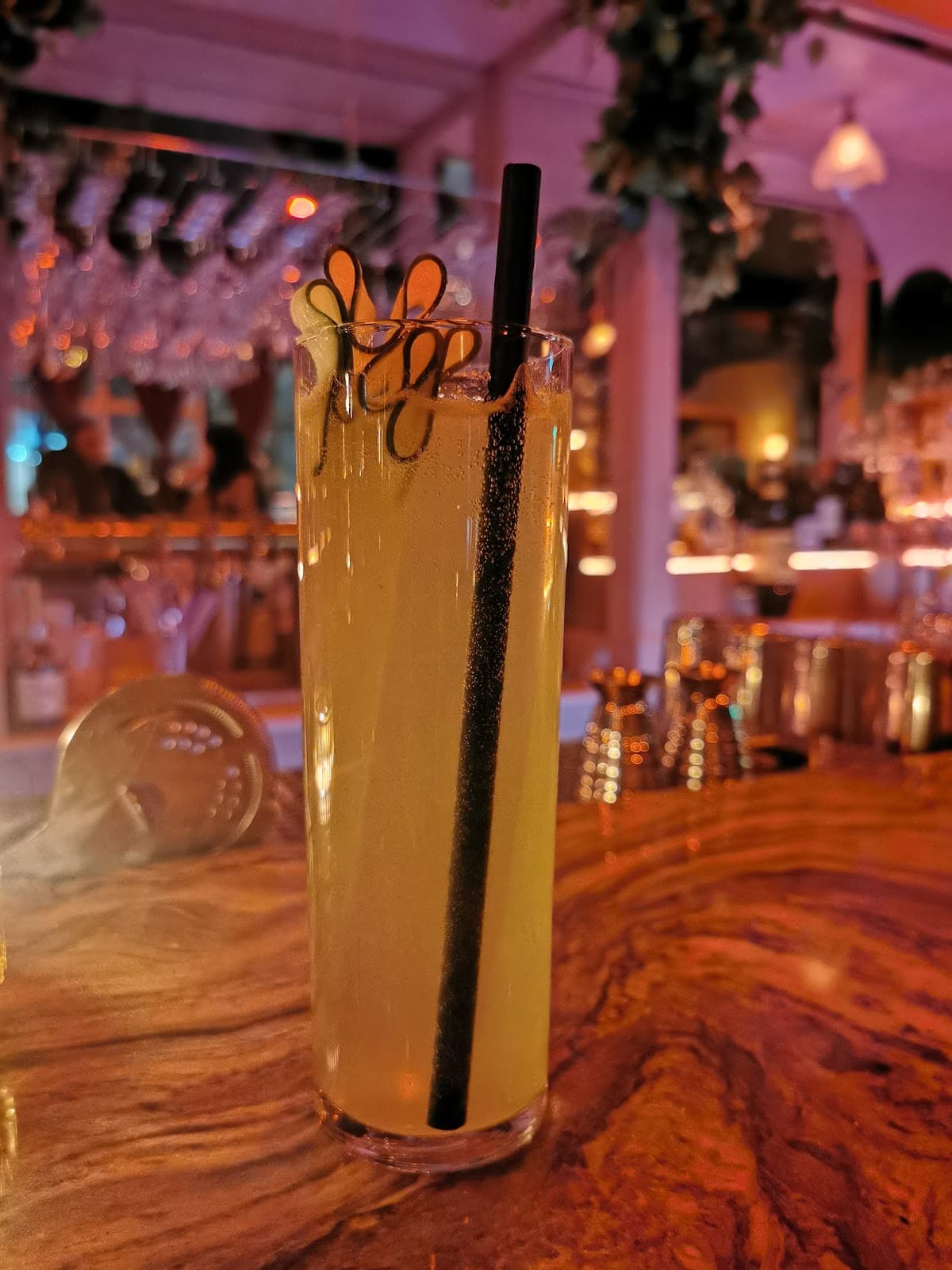 Tall cocktail glass on a bar counter with a vibrant background in Toronto