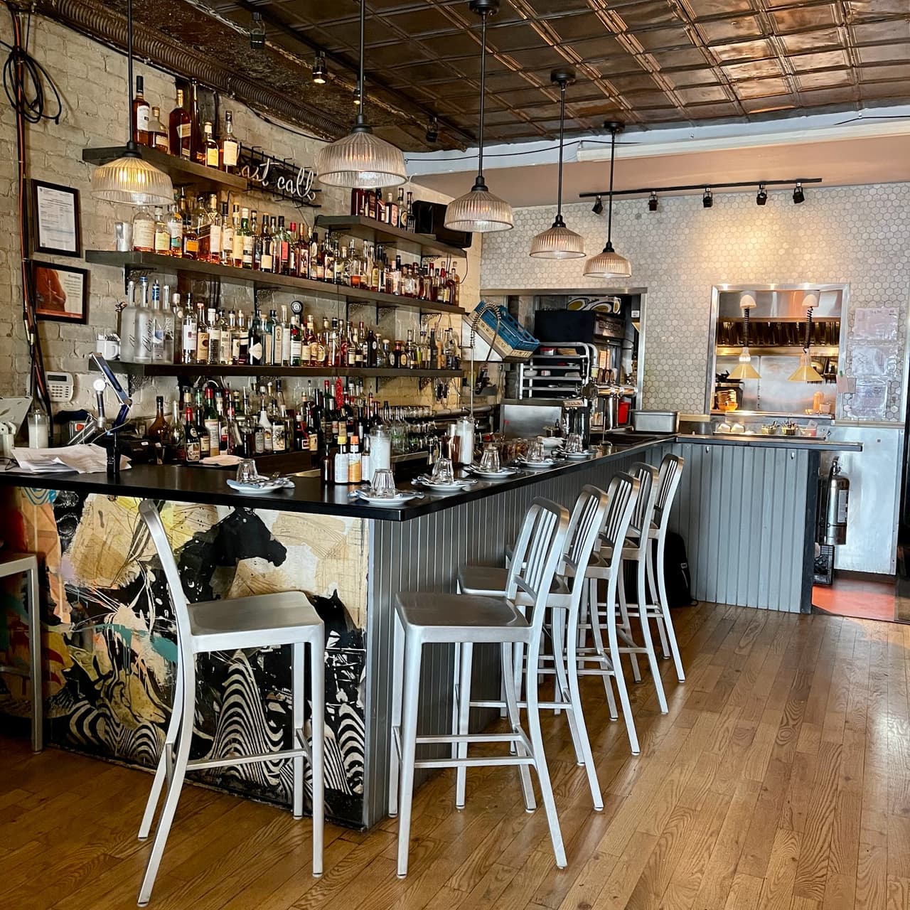 Stylish bar with metal stools, shelves of liquor bottles, and exposed brick walls