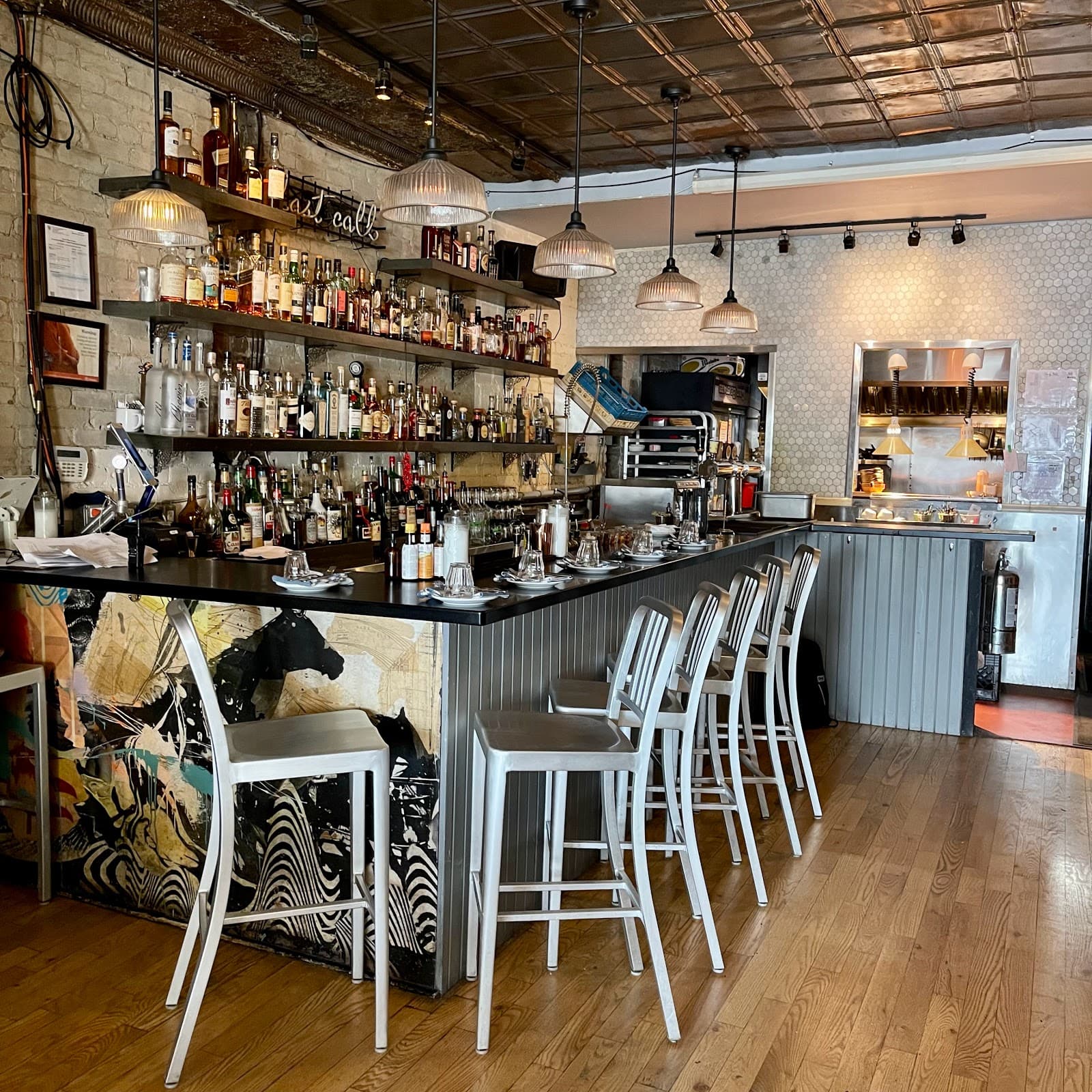 Stylish bar with metal stools, shelves of liquor bottles, and exposed brick walls