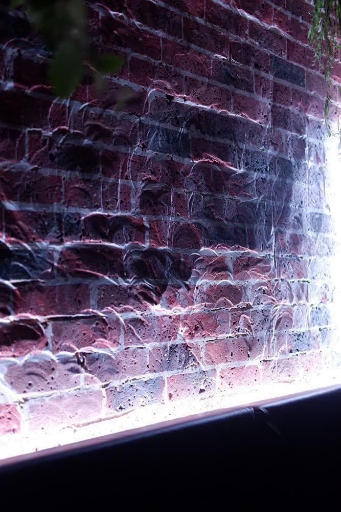 Illuminated brick wall creating moody atmosphere in cocktail bar in Paris