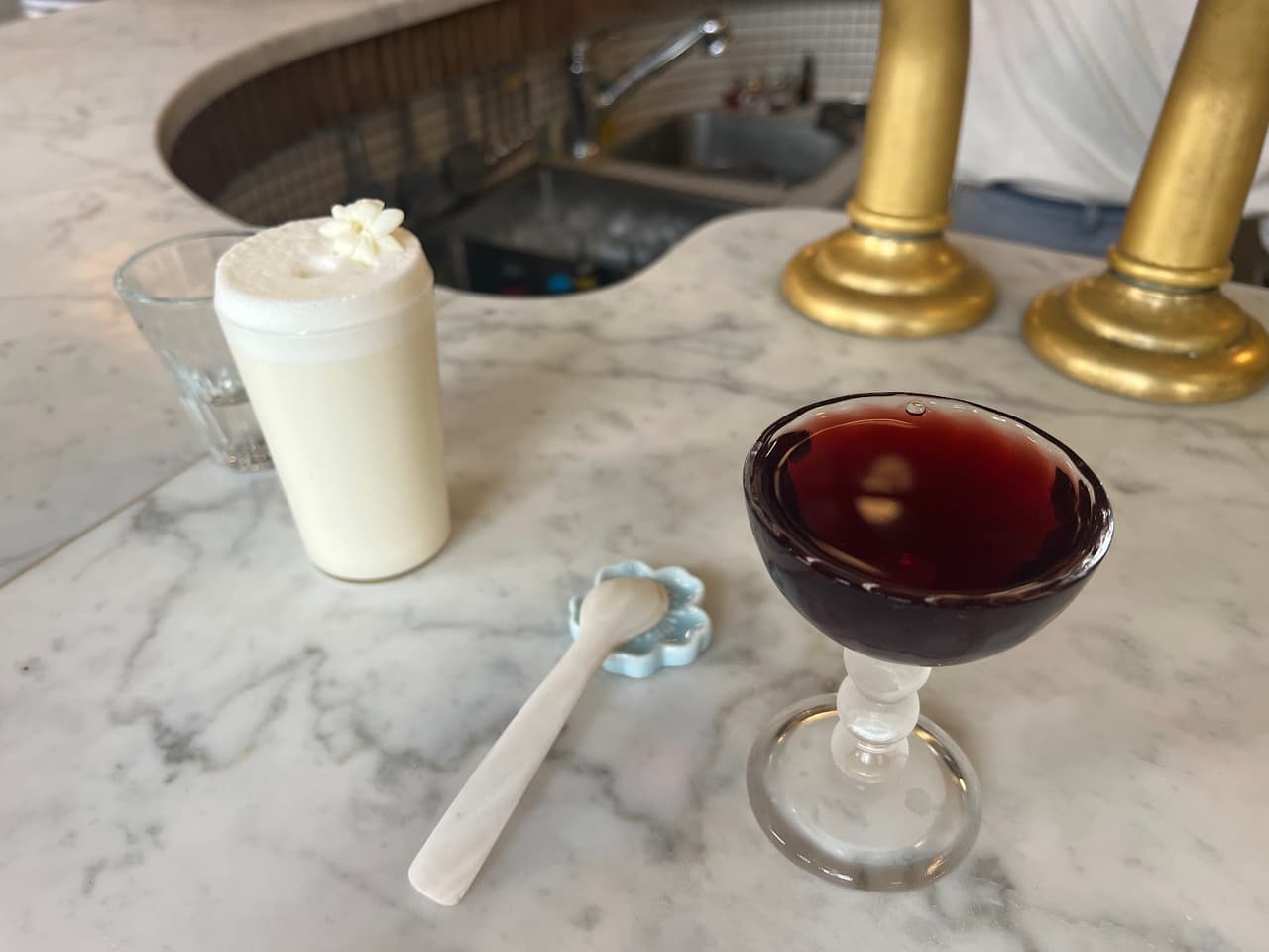 Two cocktails on a marble bar with decorative taps in the background in Paris