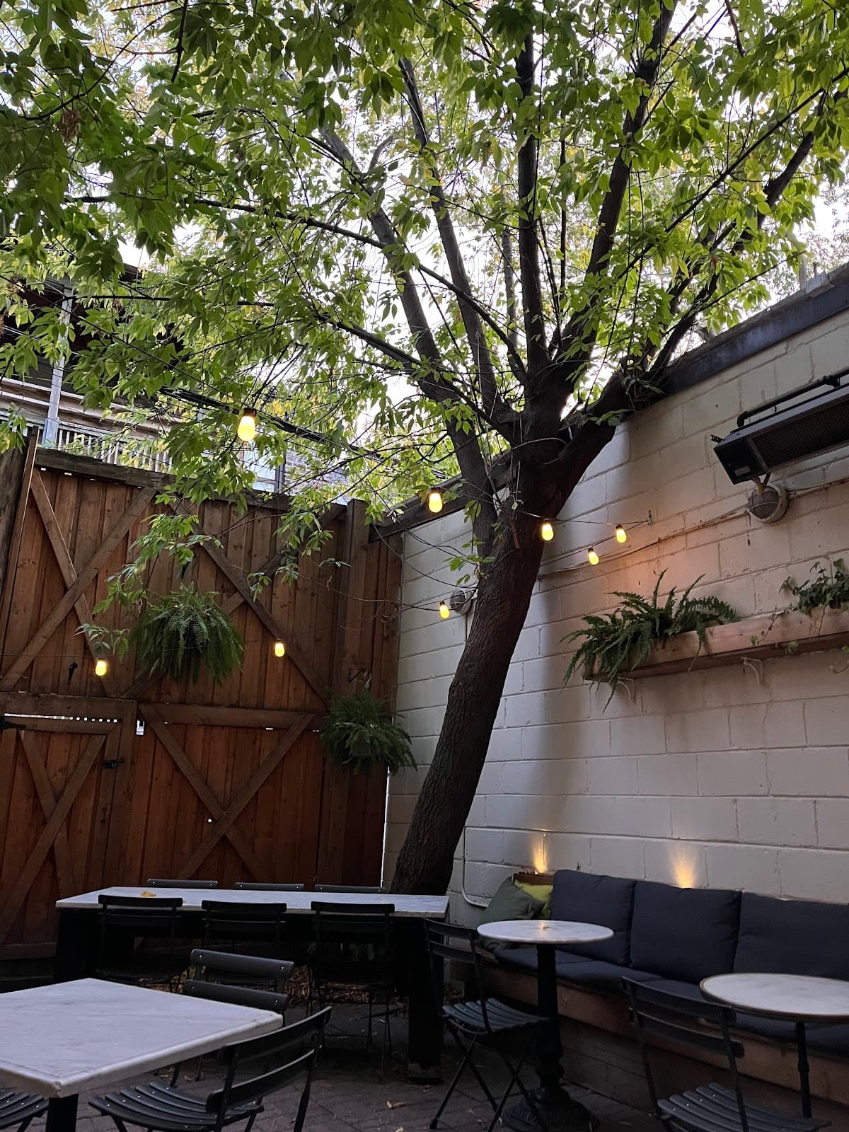 Outdoor seating area with tables, chairs, and tree with string lights in Toronto