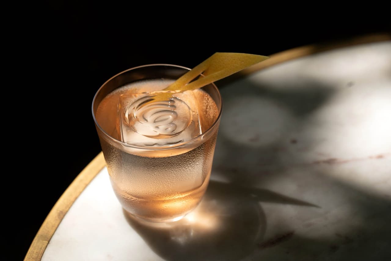 Chilled cocktail with a large ice cube and lemon twist on a marble table in Toronto