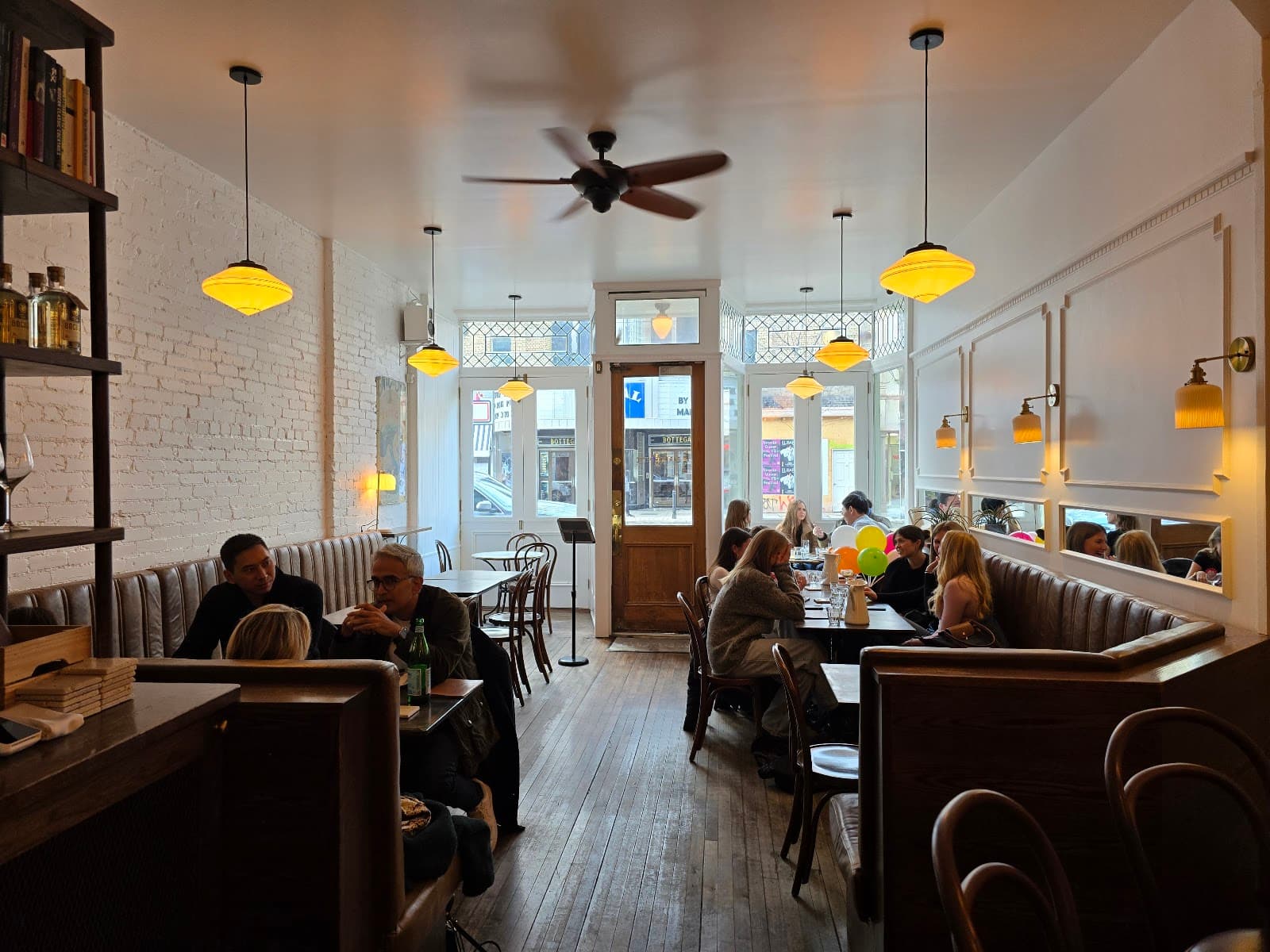 Cozy interior with booths and hanging lights in a busy cocktail bar in Toronto