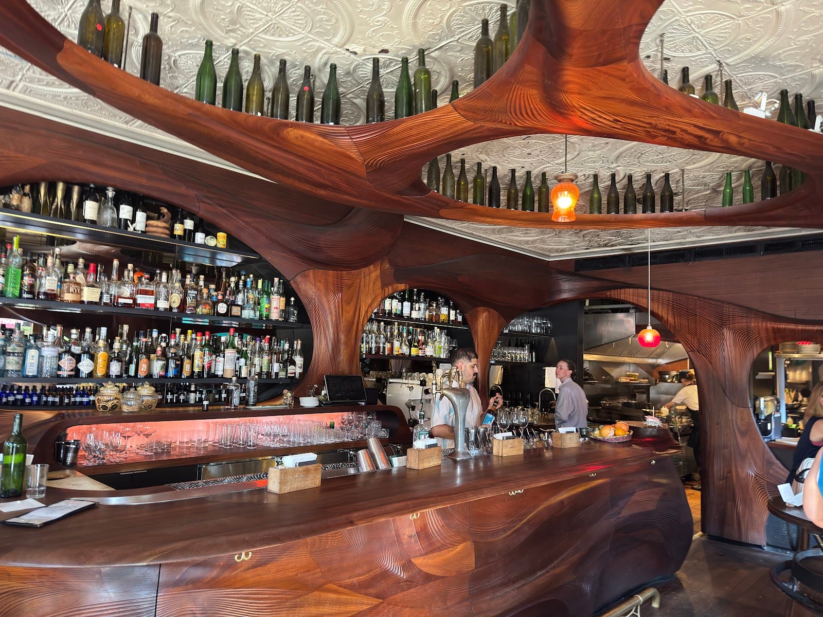 Stylish bar counter with wooden design and shelves of bottles.