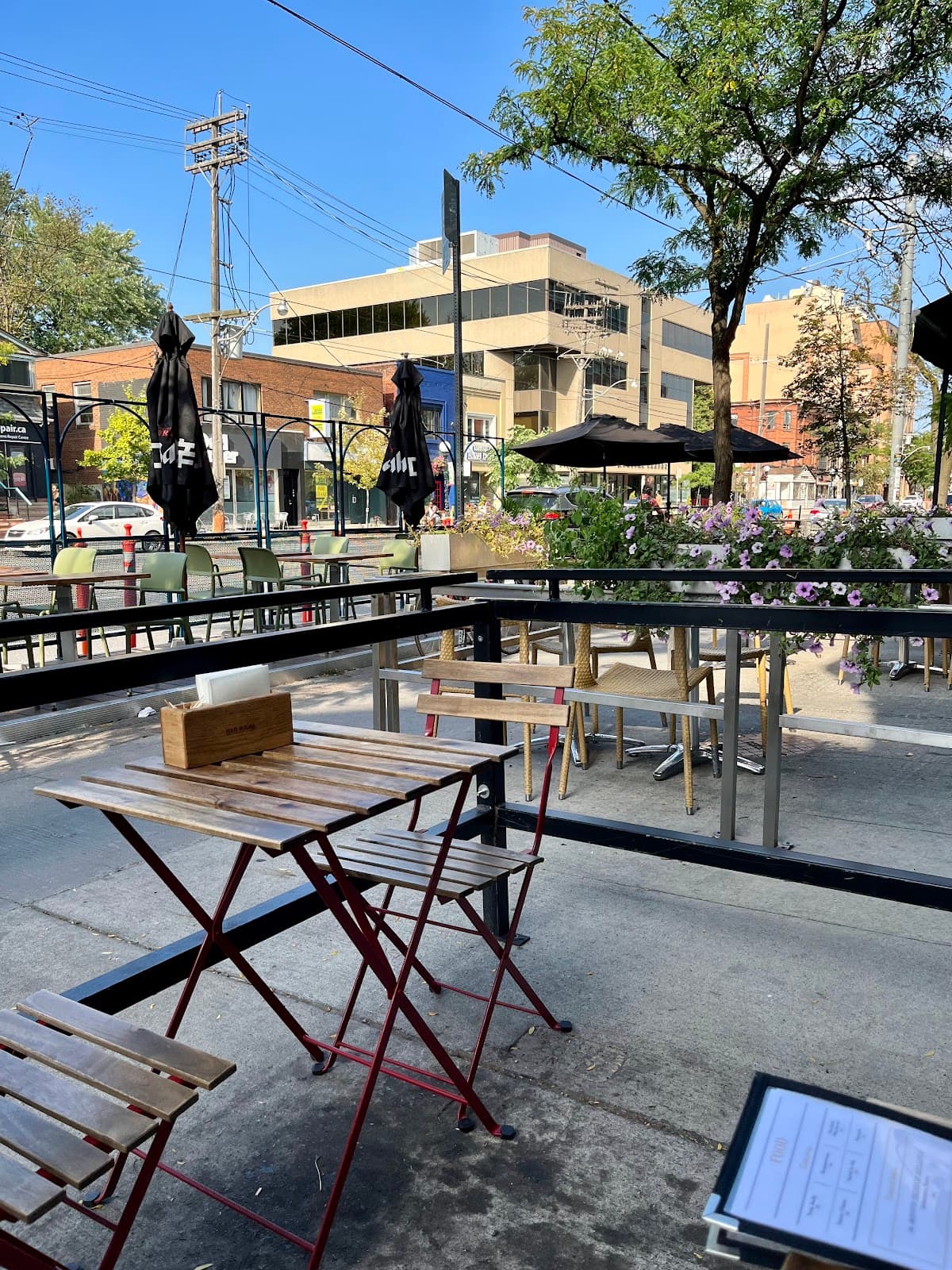 Outdoor seating area with wooden tables under a clear sky in Toronto
