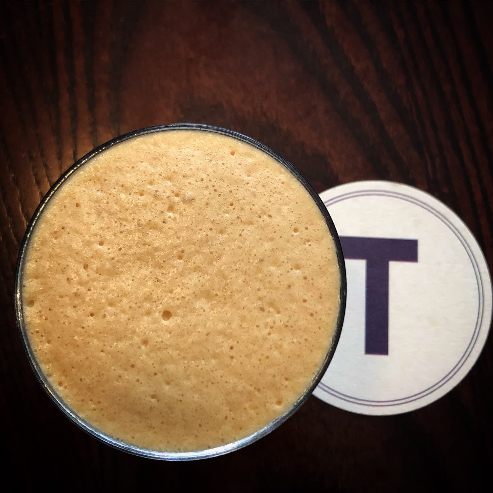 Creamy cocktail on wooden table with coaster in London