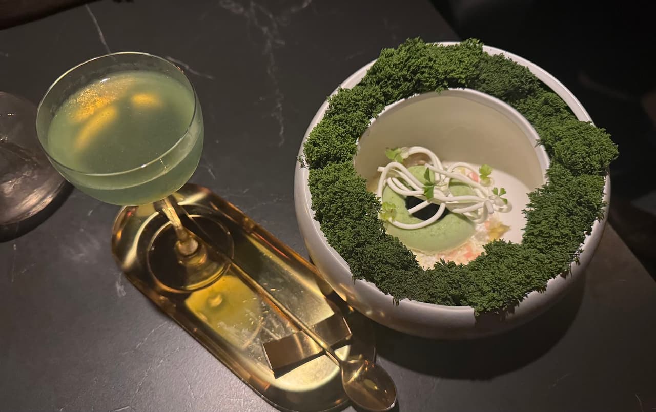 Elegant green cocktail served on a dark table with a decorative dish. in Toronto