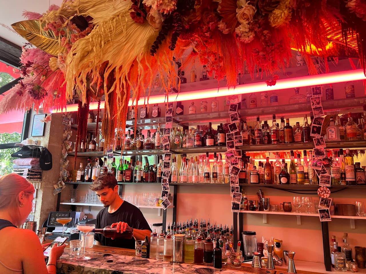 Bartender preparing cocktails at a colorful, decorated bar in Paris