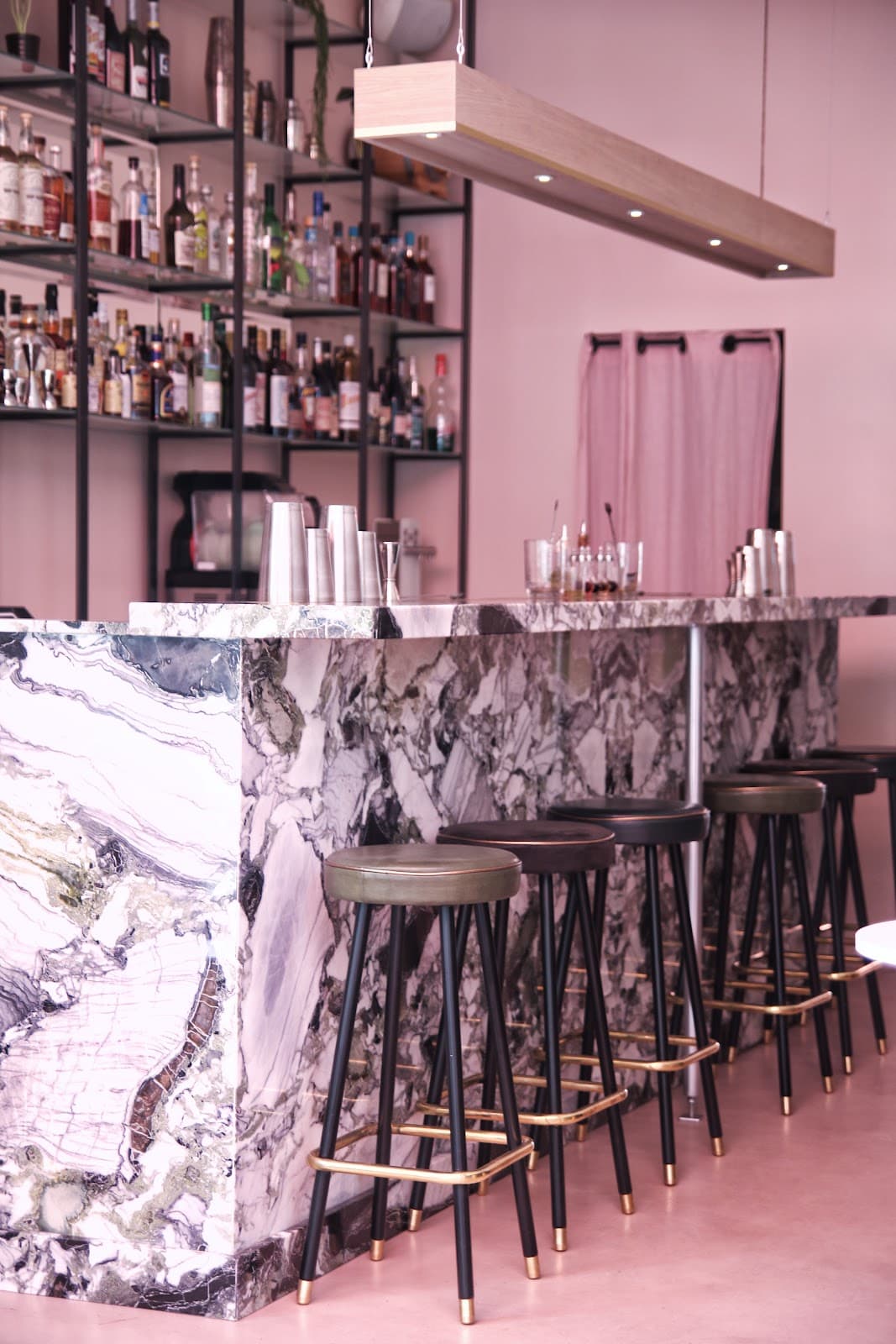 Chic marble bar with stools and shelves of bottles in a cocktail bar