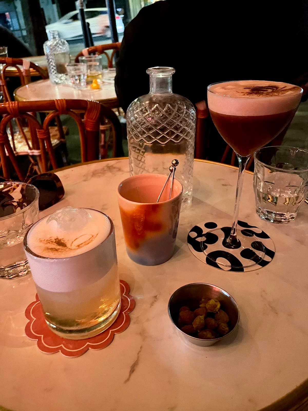 Cocktail drinks on a table with a glass bottle and snacks in Paris