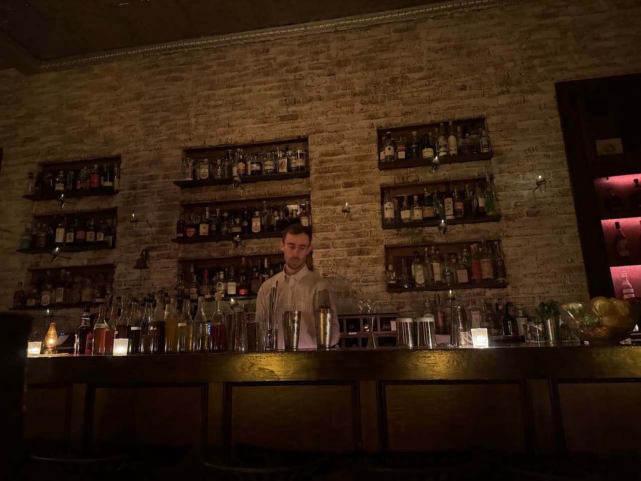 Dimly lit bar with shelves of bottles and a bartender in front in San Francisco