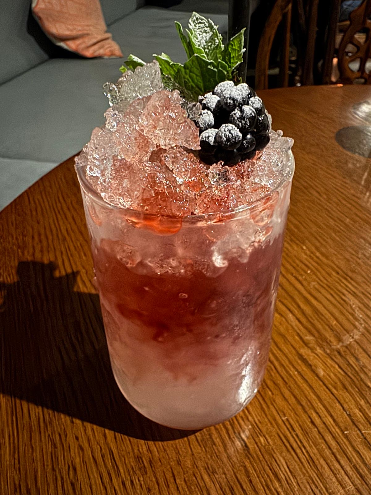 Cocktail with crushed ice, mint, and berries on a wooden table in Edinburgh