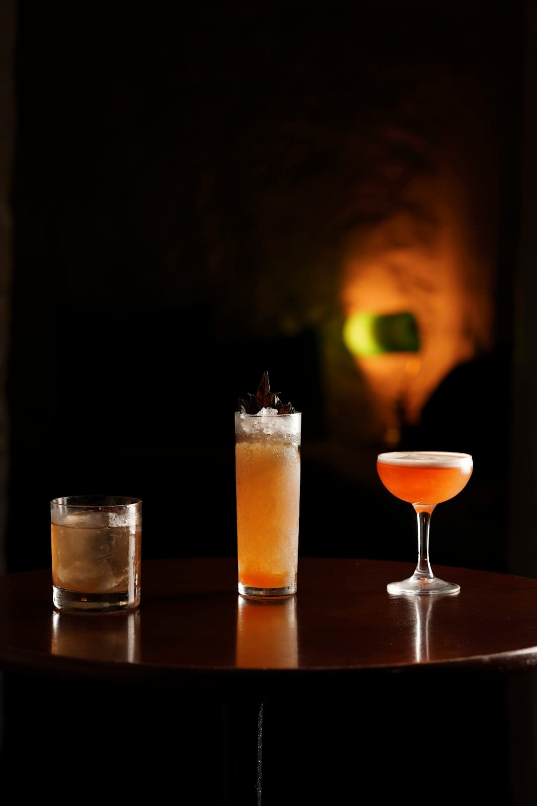 Three cocktails on a dark wooden table with warm ambient lighting in Edinburgh