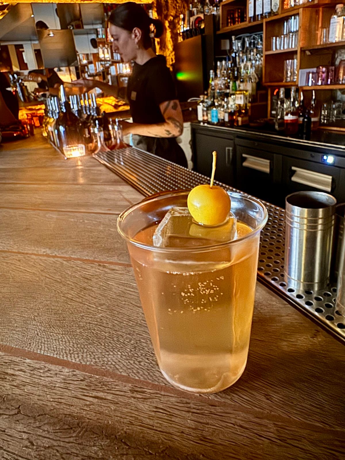 Bar counter with a cocktail and bartender in background in Paris