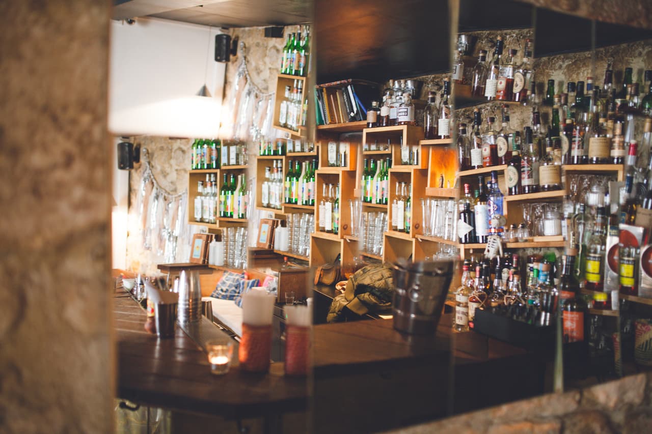 Cozy bar area with shelves full of liquor bottles and dim lighting