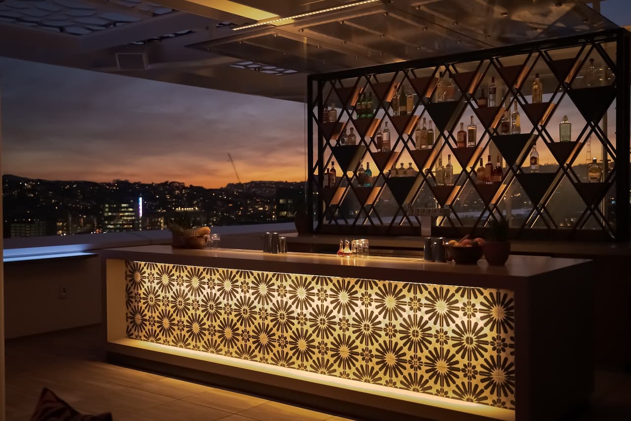 Stylish rooftop bar with illuminated counter and city skyline at sunset