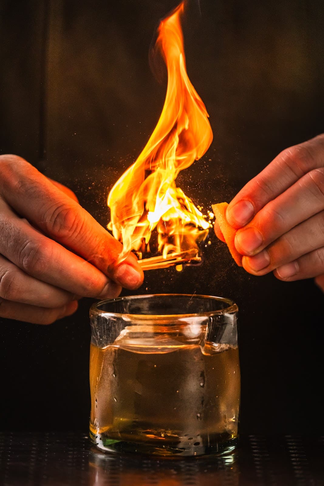 Bartender setting a cocktail on fire with orange peel in San Francisco