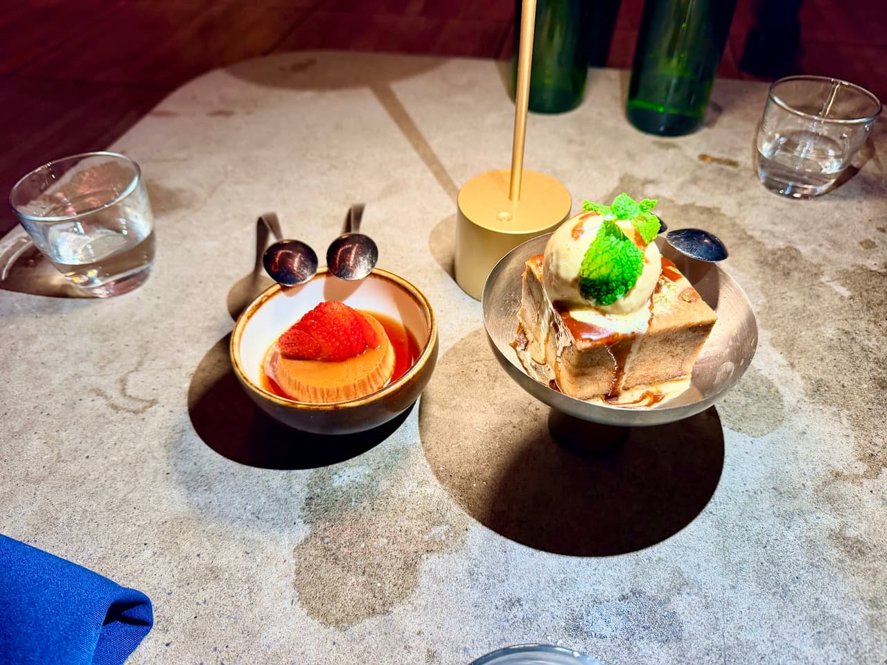 Two dessert bowls on a concrete table in a bar setting in San Francisco