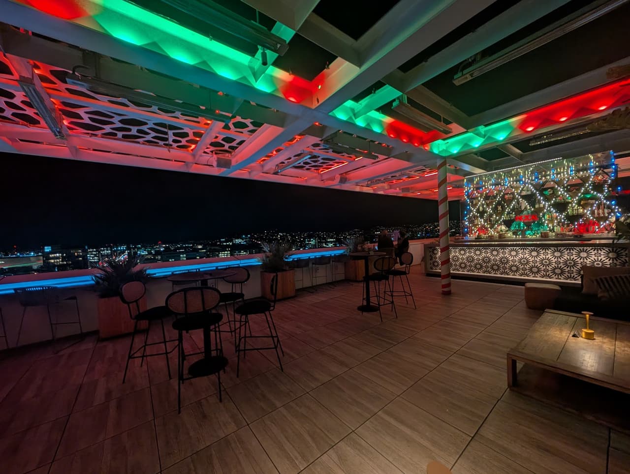 Rooftop bar with colorful lighting and city skyline view at night in San Francisco