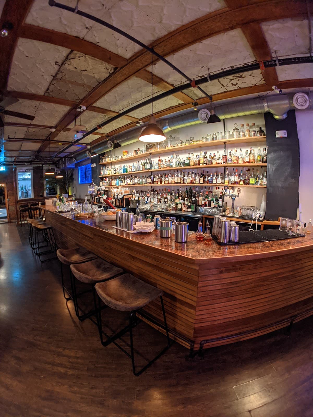 Cozy bar interior with a well-stocked bar and wooden stools in Toronto