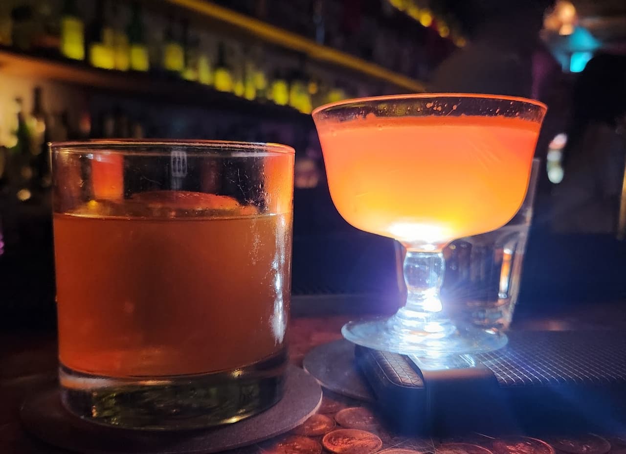 Two cocktails on a bar counter with dim lighting in Toronto